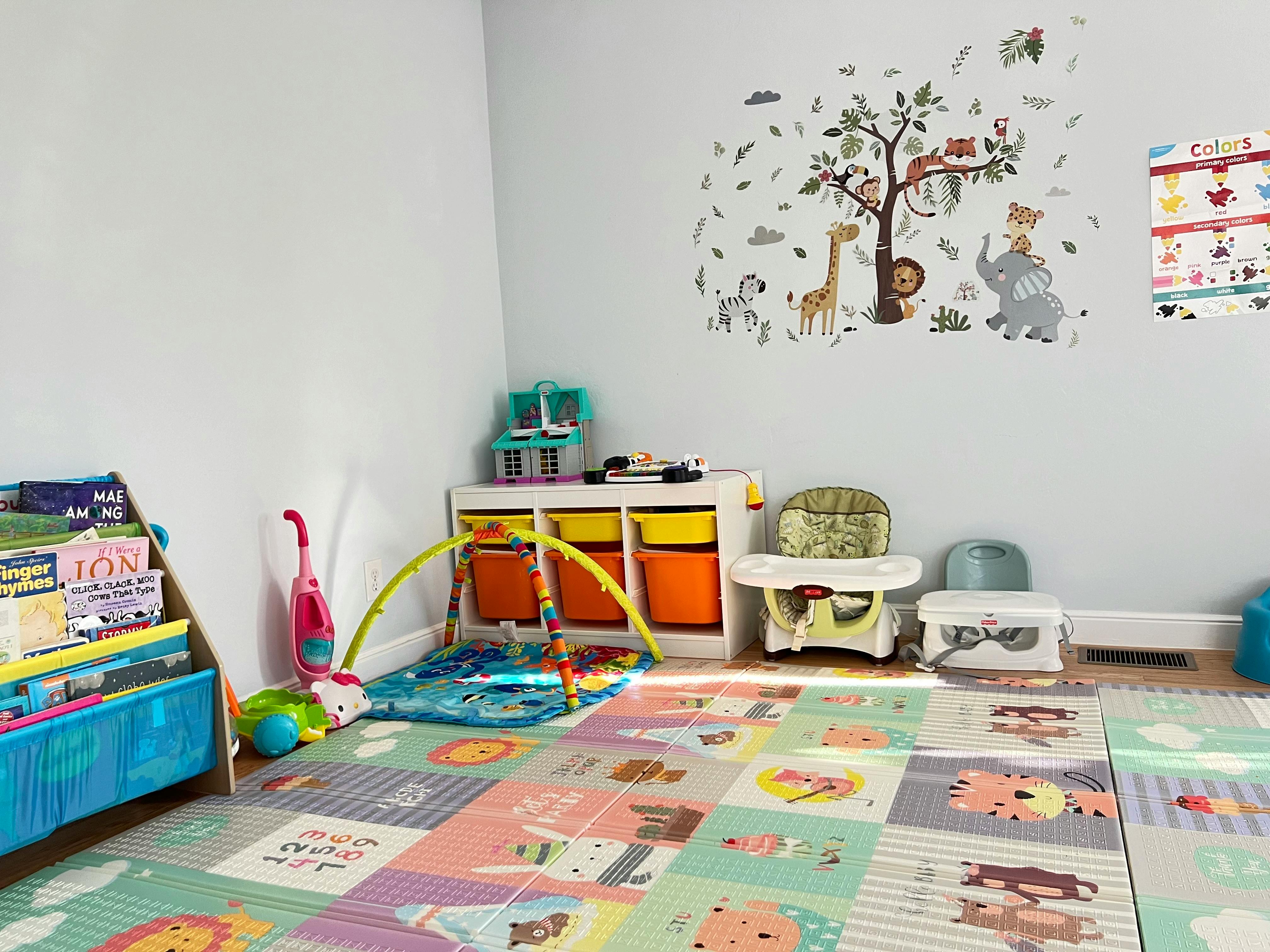 Playroom with colorful floor mats, toys, and wall decals