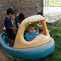 Child in a toy boat with other children nearby