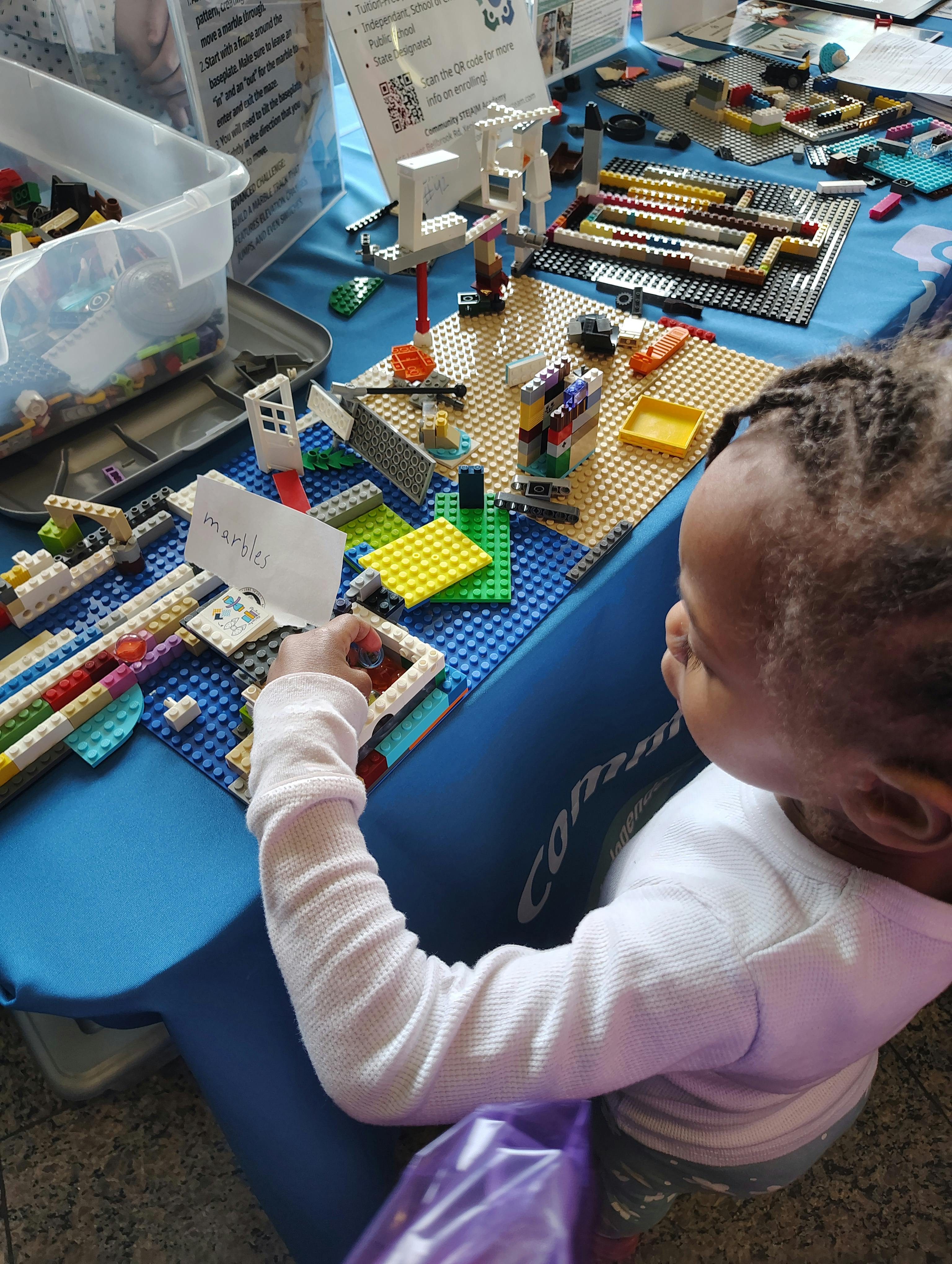Child building a marble run with colorful Lego bricks