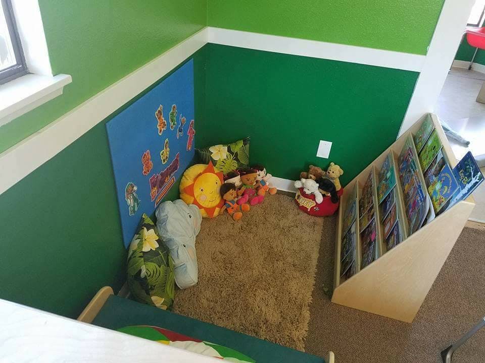 Corner of a room with a rug, stuffed animals, and a bookshelf