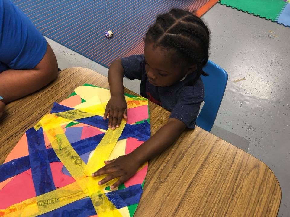 Child working on a colorful art project at a table