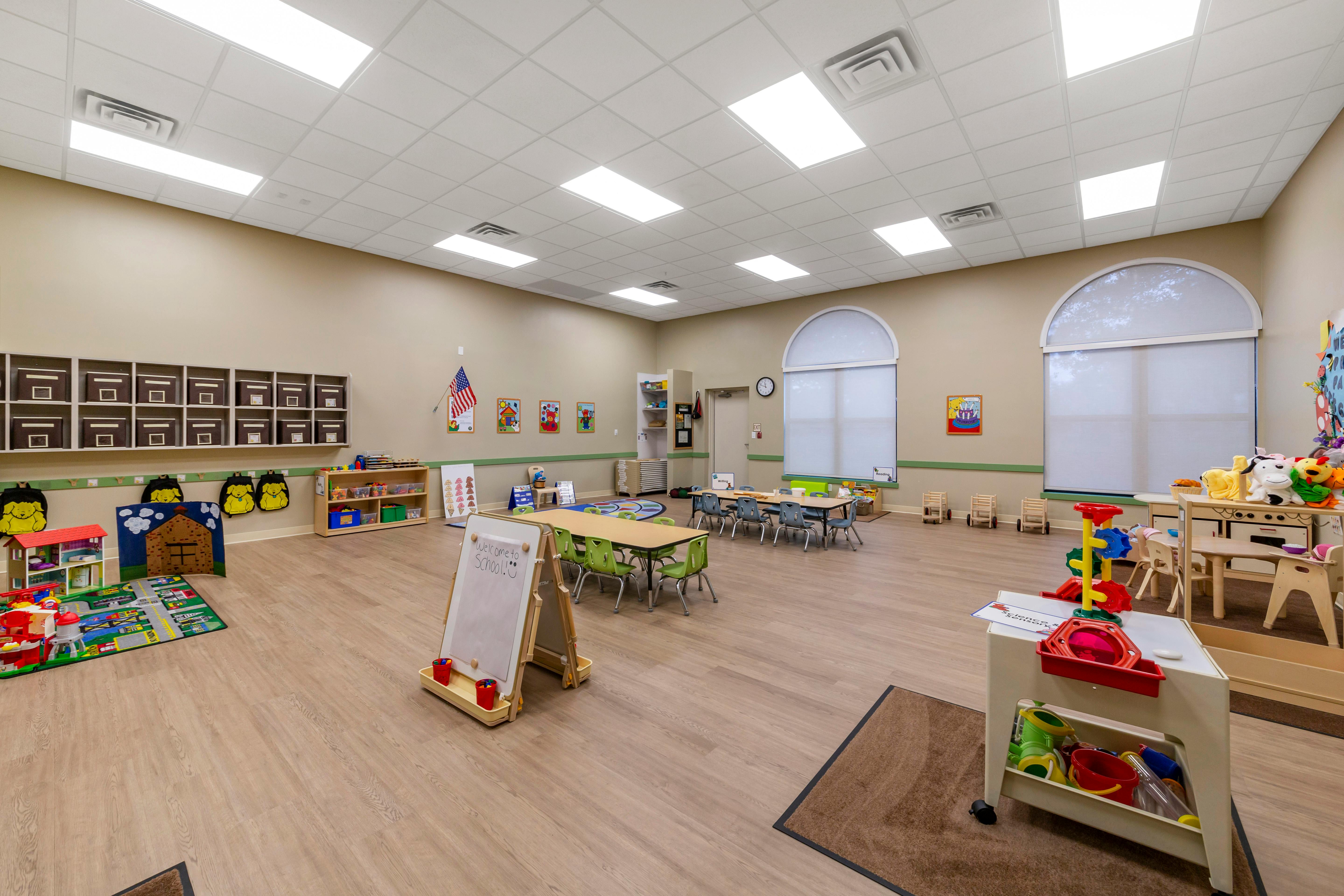 An empty early childhood classroom with toys, tables, and a whiteboard