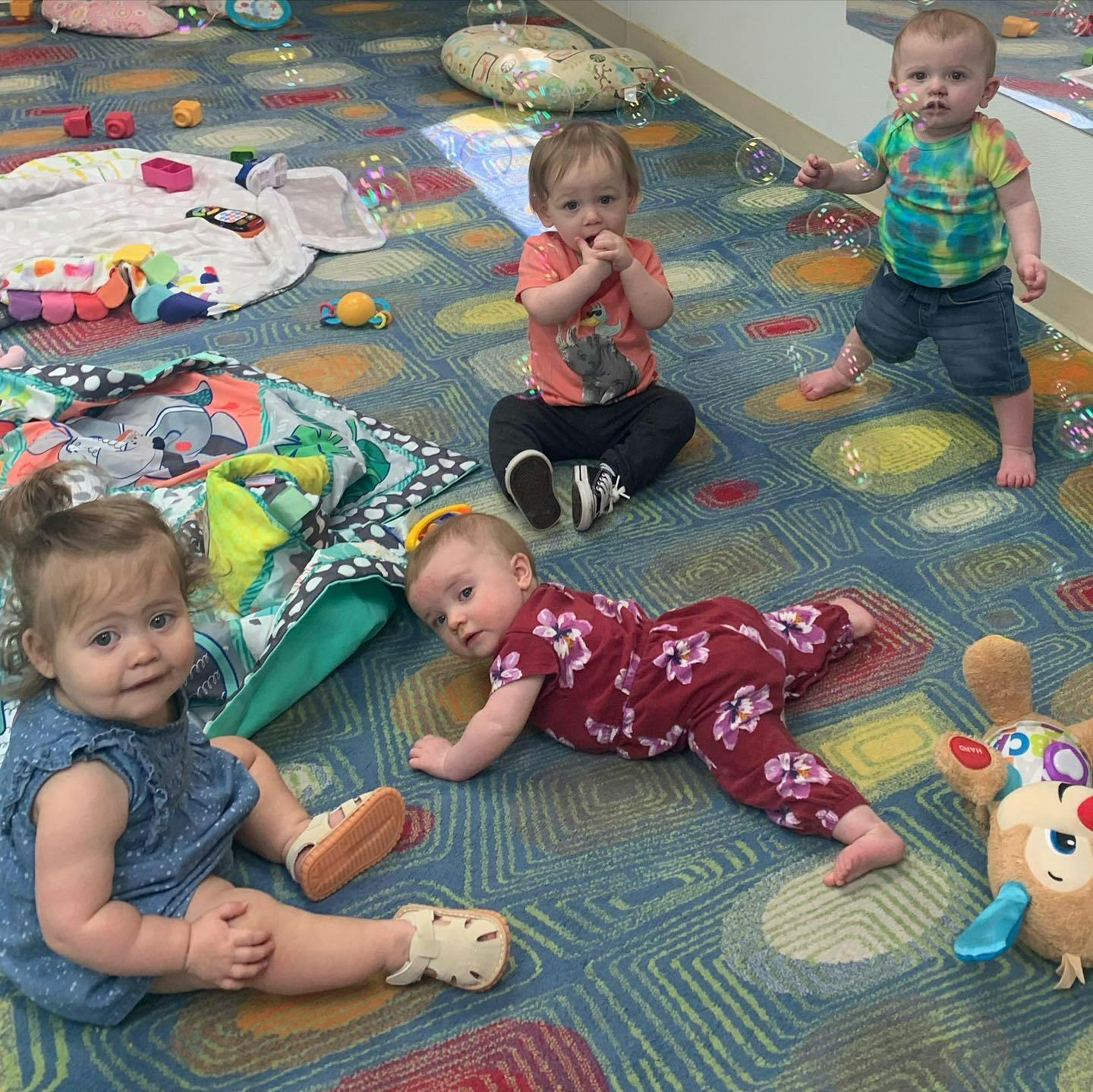 Four children playing on a colorful carpet