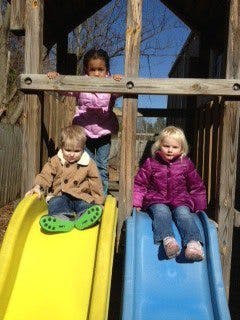 Three children on a playground structure with two slides