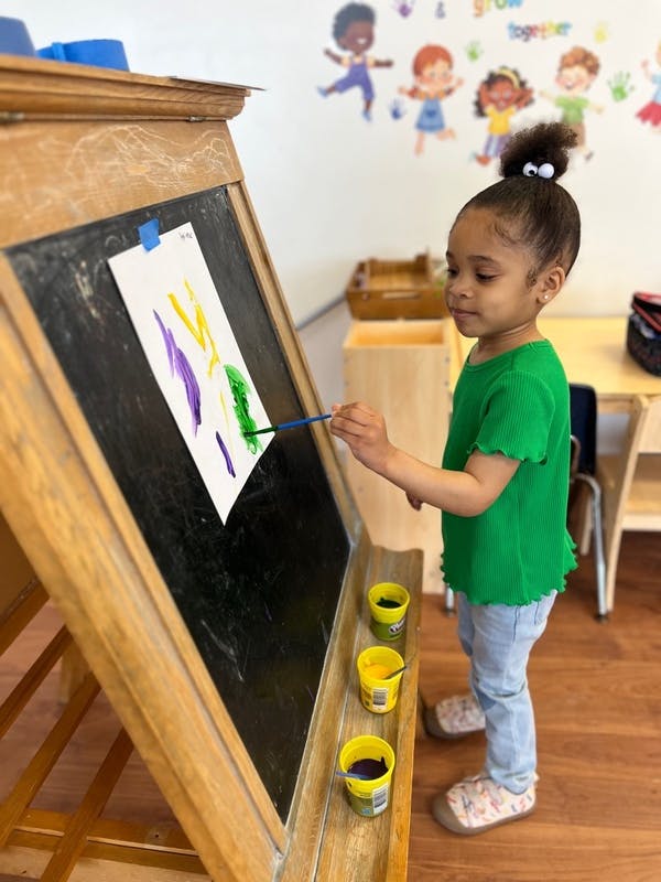 Child painting on an easel in a classroom