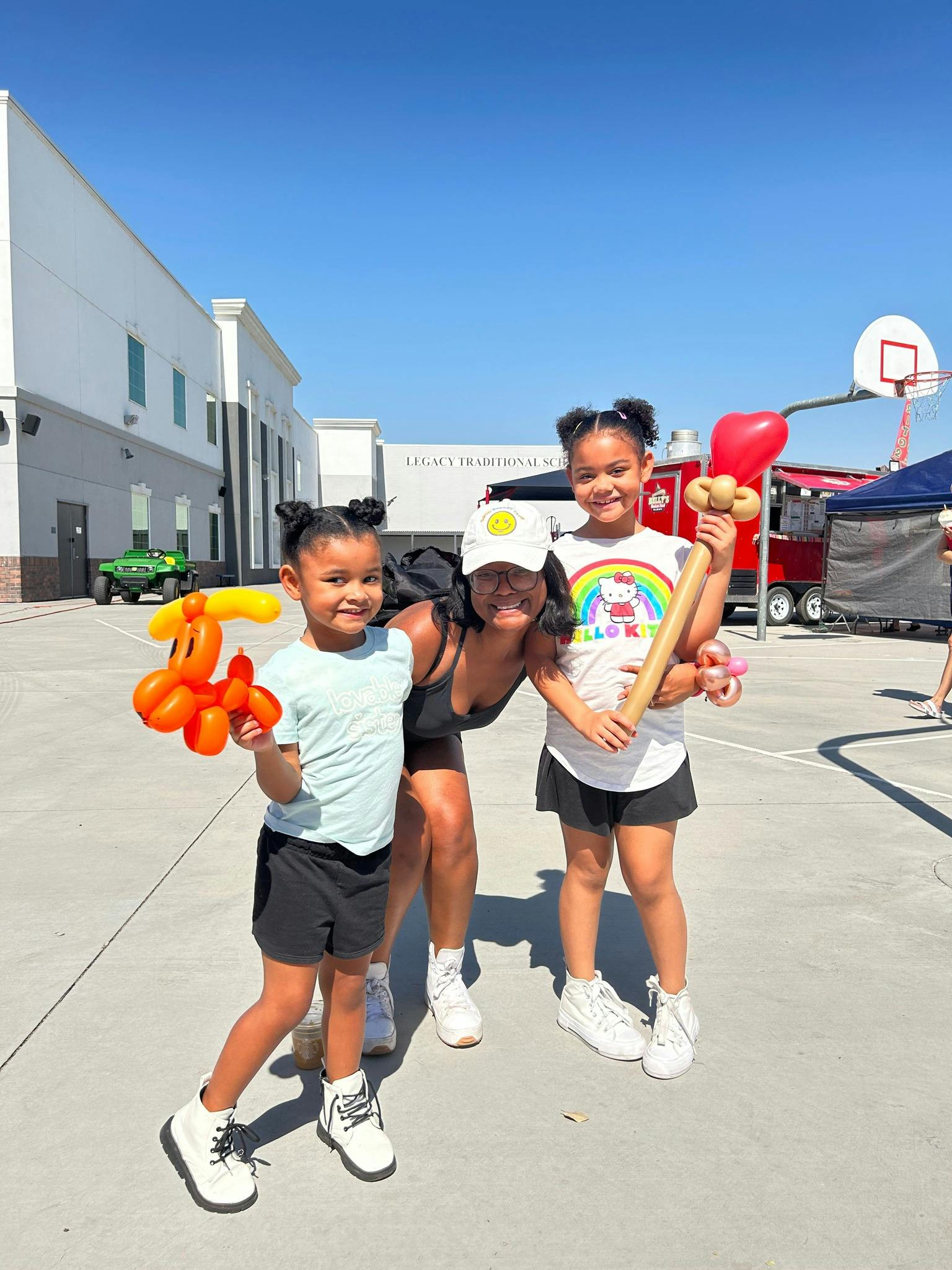 Person with two children holding balloon animals outdoors