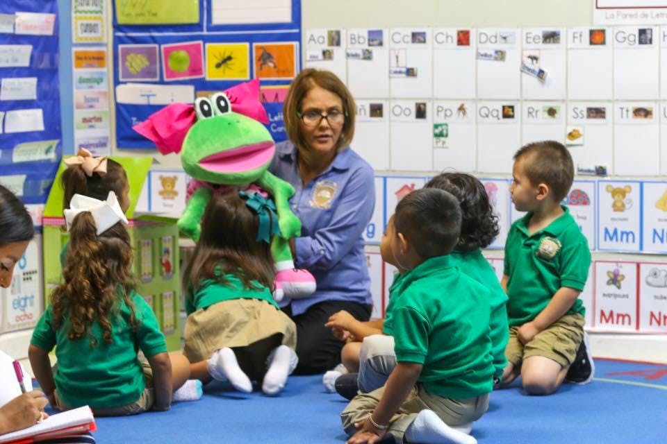 Adult with a frog puppet interacting with children in a classroom