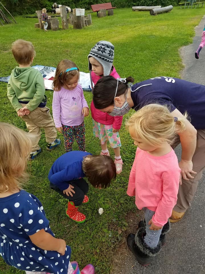 Adult and children looking at something on the ground