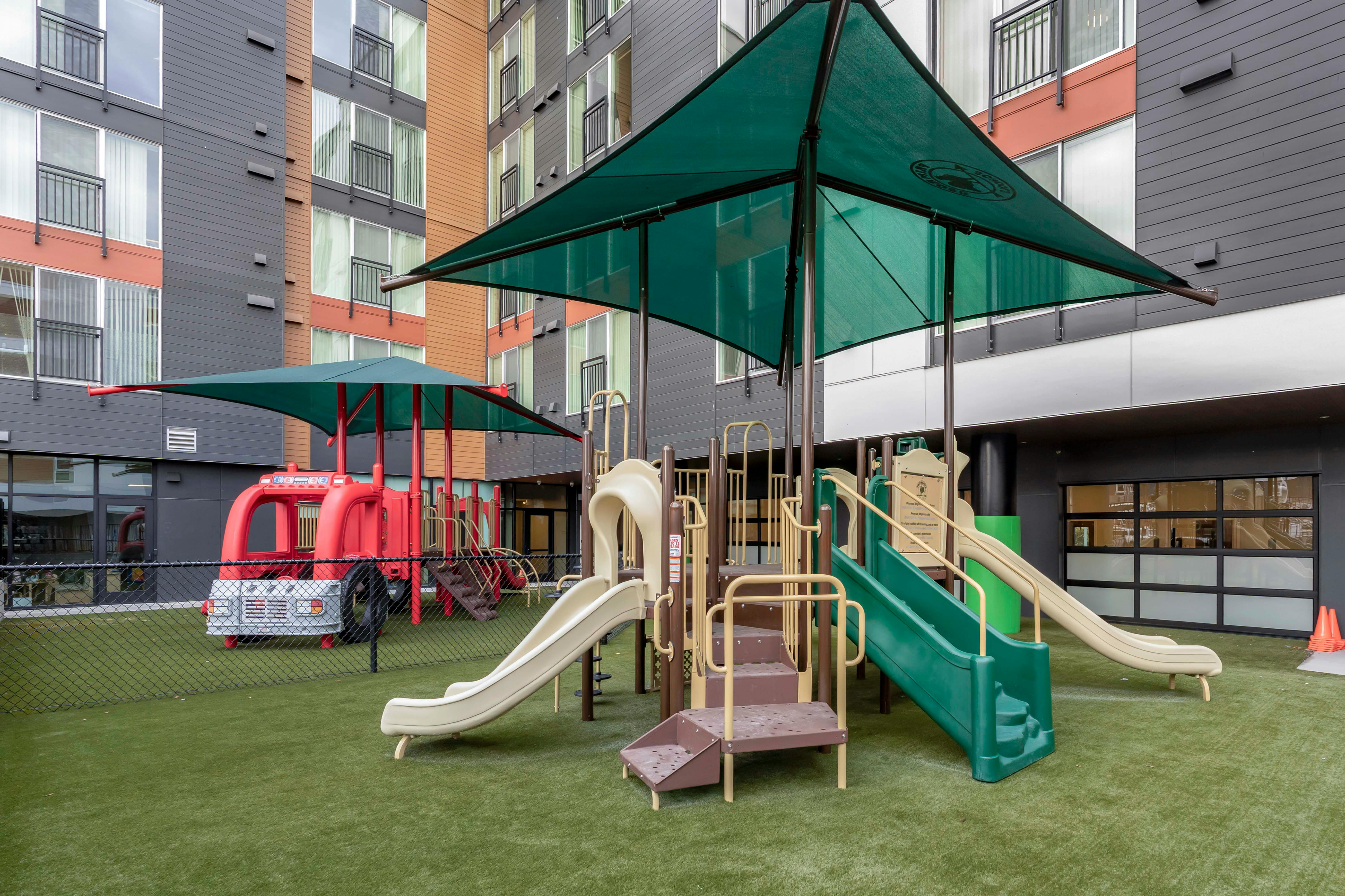Outdoor playground with slides and climbing structures on artificial turf