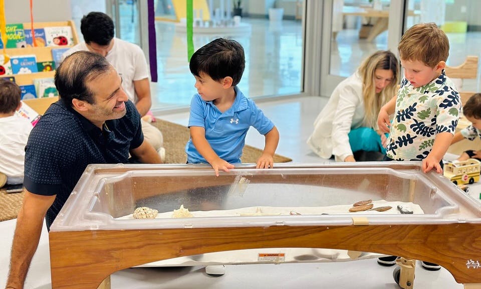 Adult and child looking at a sand table