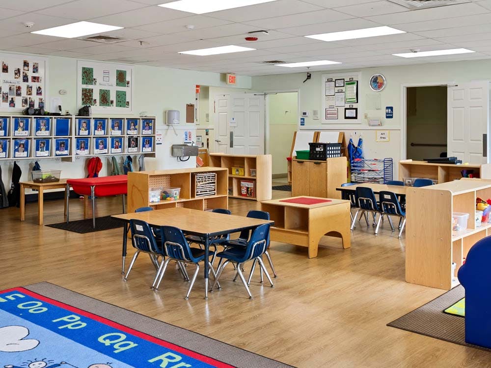 Empty classroom with small tables and chairs, shelves, and cubbies