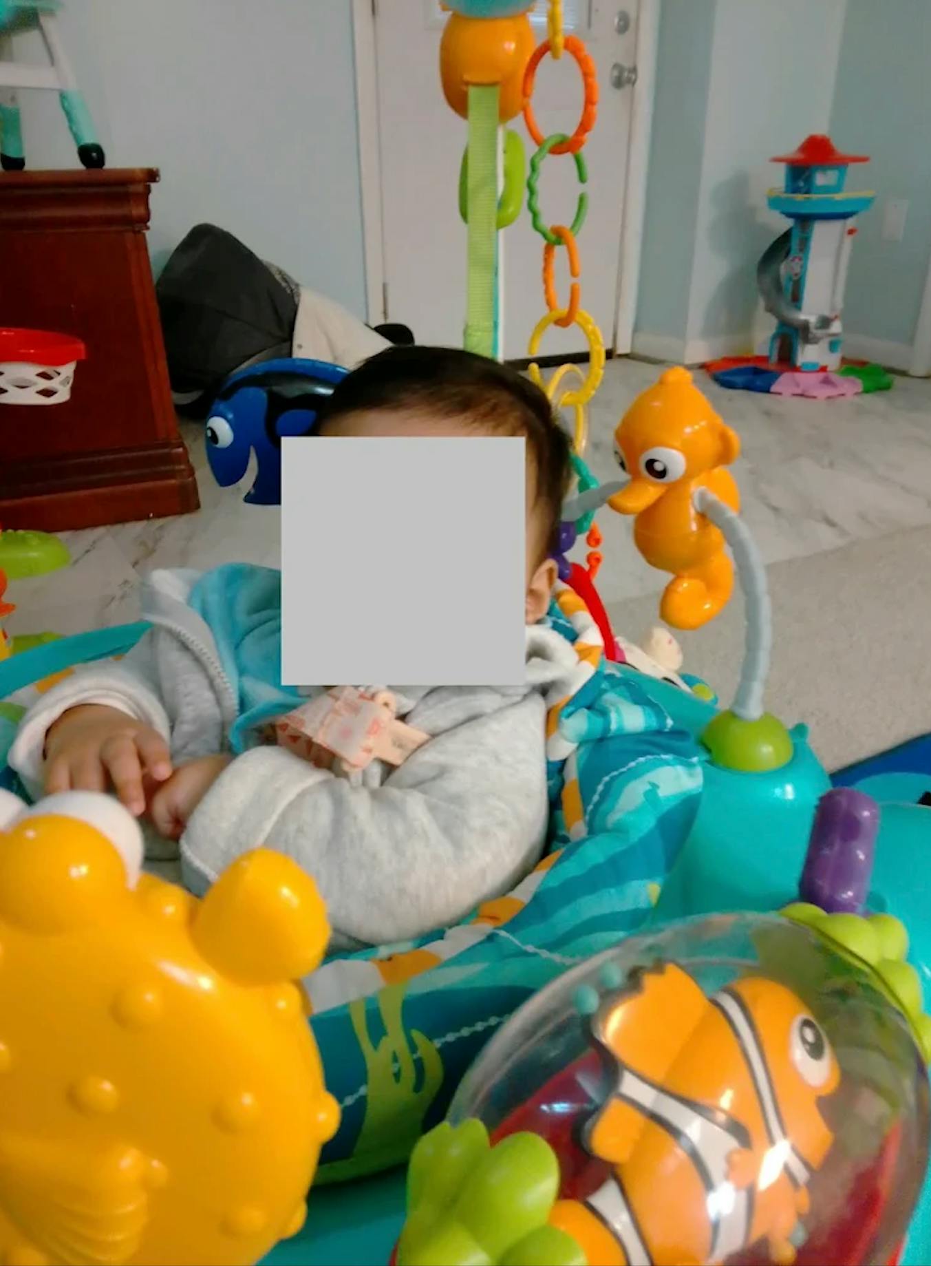 Child sitting in an activity center with hanging aquatic toys
