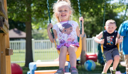 Child on a swing with another child in the background
