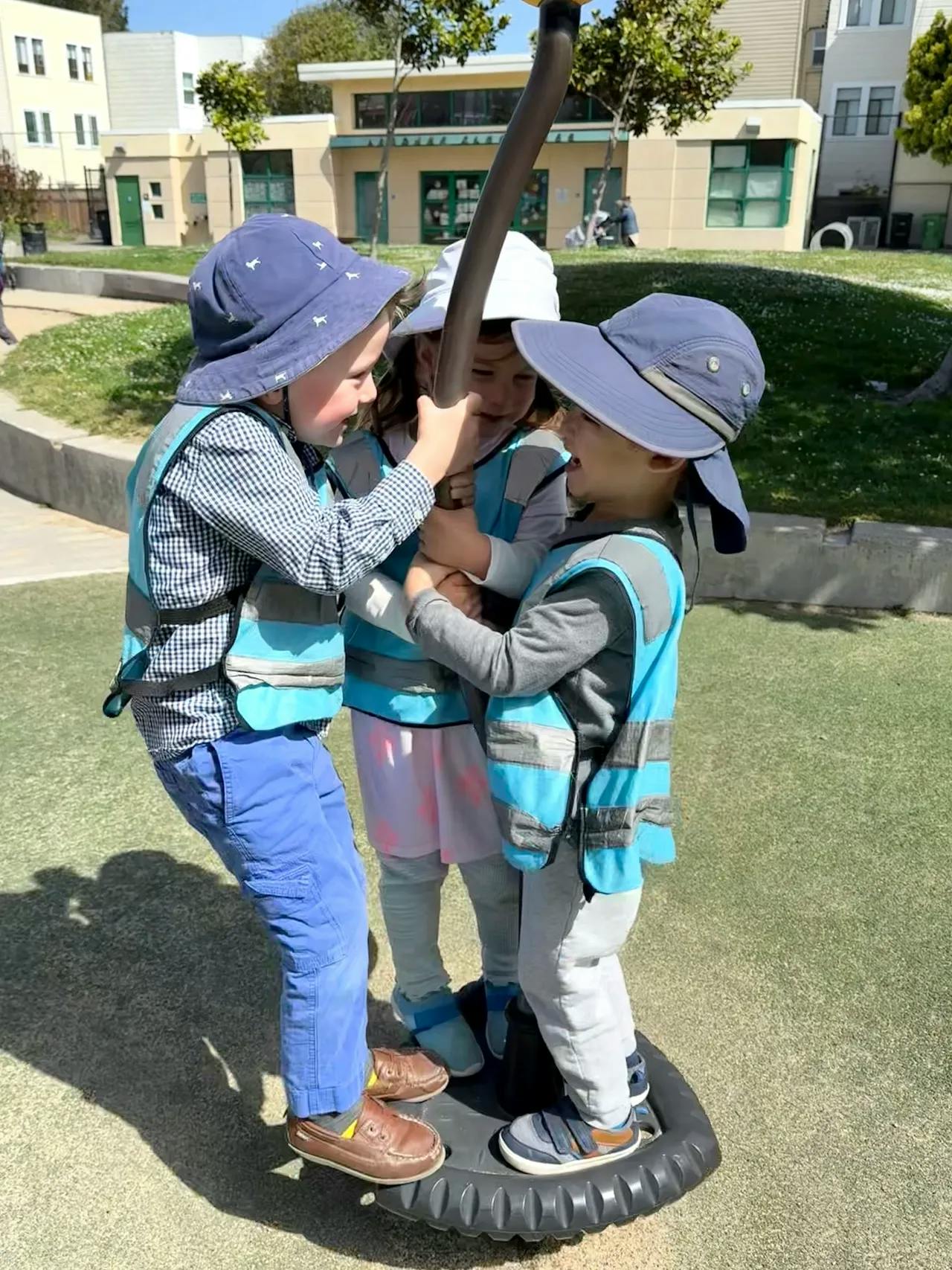 Three children playing on a spinning playground toy
