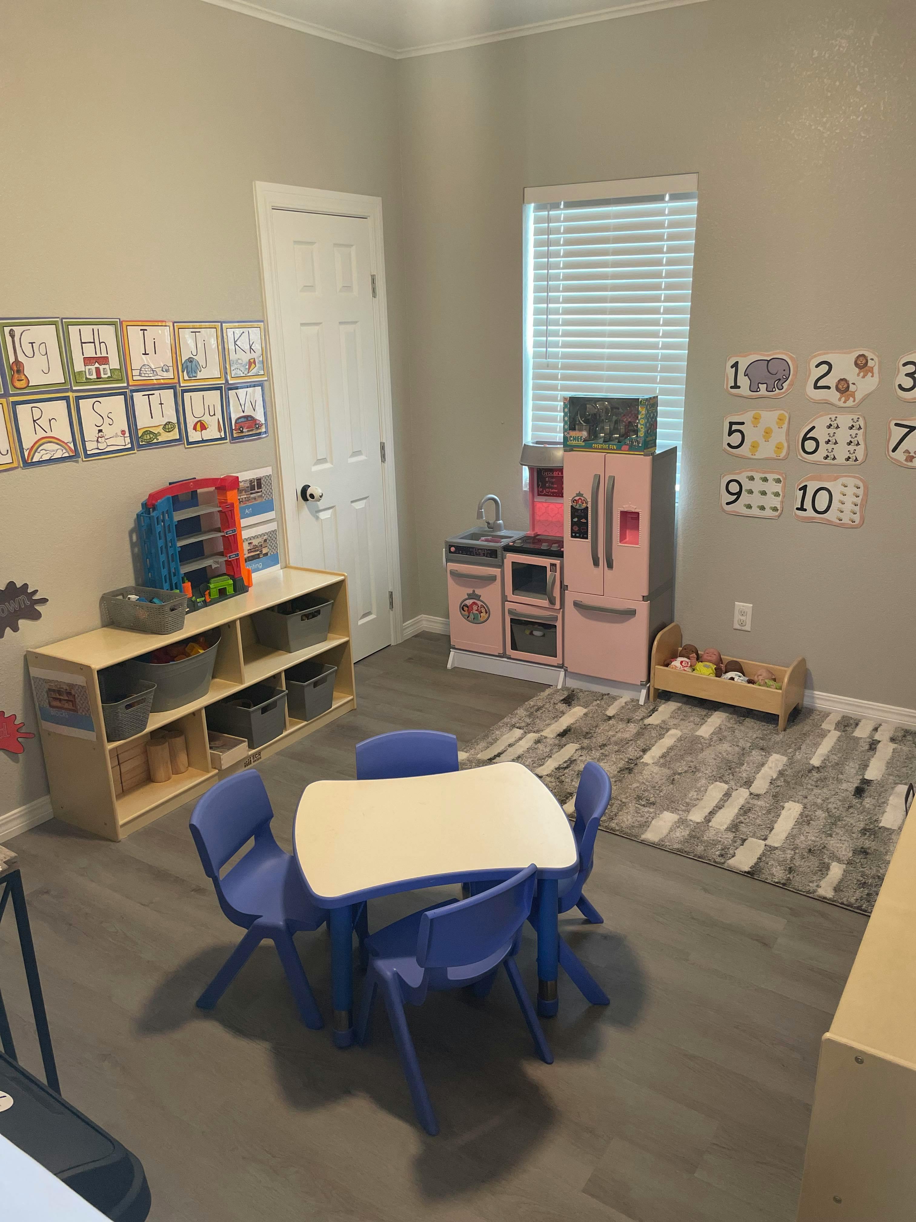 Playroom with a small table and chairs, toy kitchen, and storage shelves