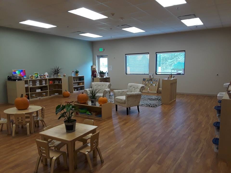 Classroom with small tables and chairs, bookshelves, and armchairs