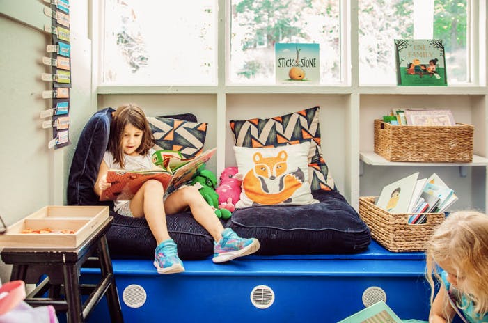 Child sitting on a cushion reading a book
