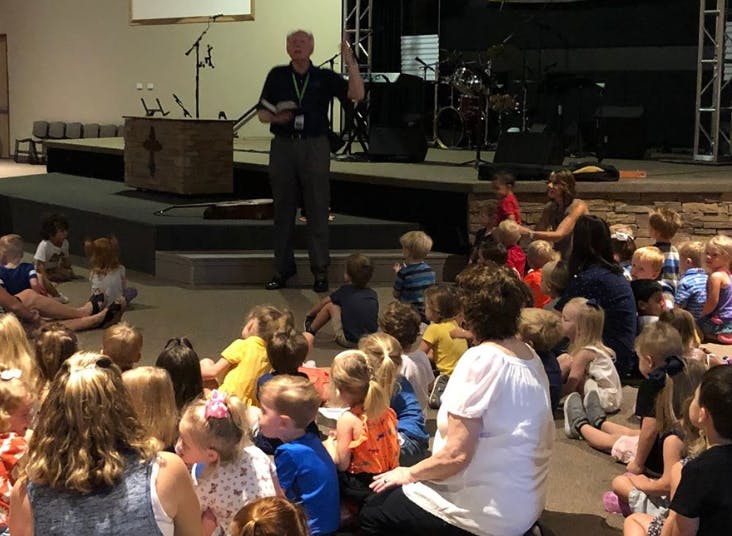 Person speaking to a group of children and adults
