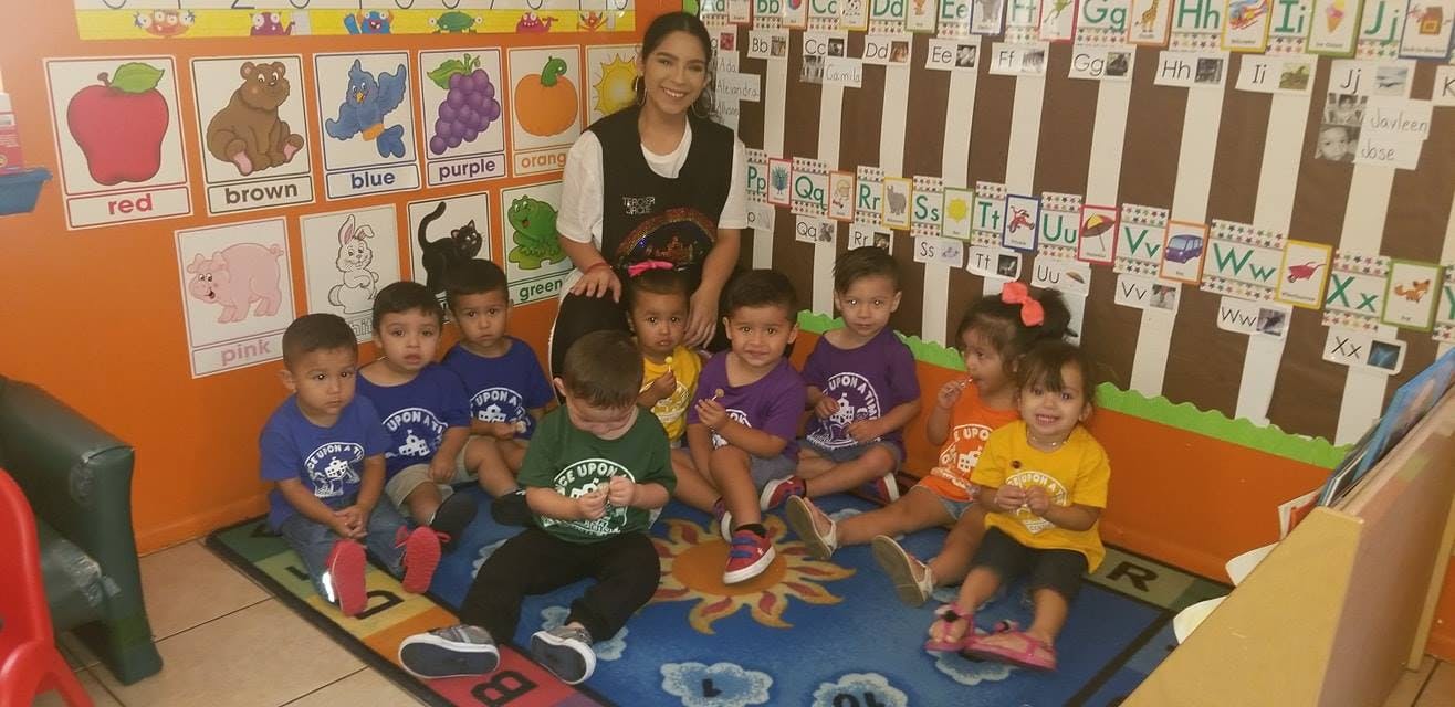 Adult and multiple children sitting on a rug in a classroom
