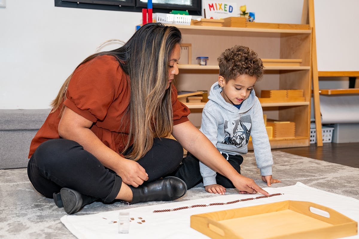 Person and child on floor arranging small pieces