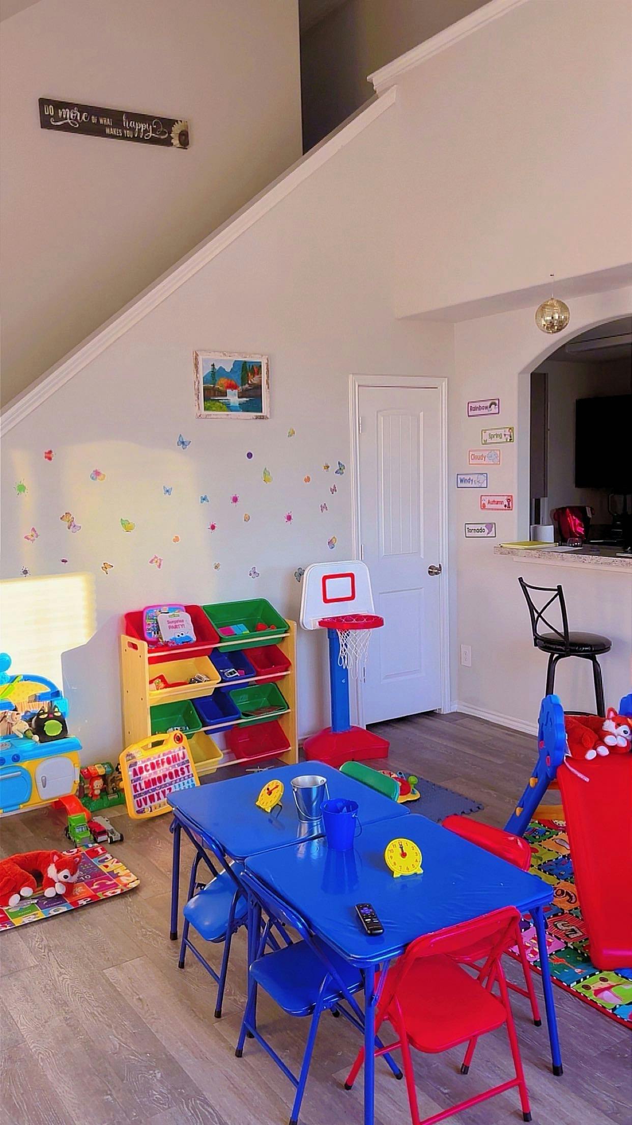 Children's play area with a blue table, chairs, toy organizer, and mini basketball hoop