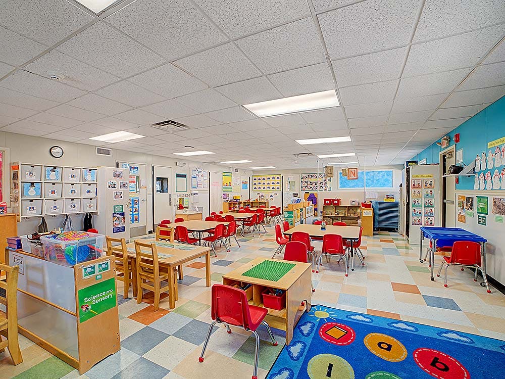 Classroom with small tables and chairs, shelves, and decorations
