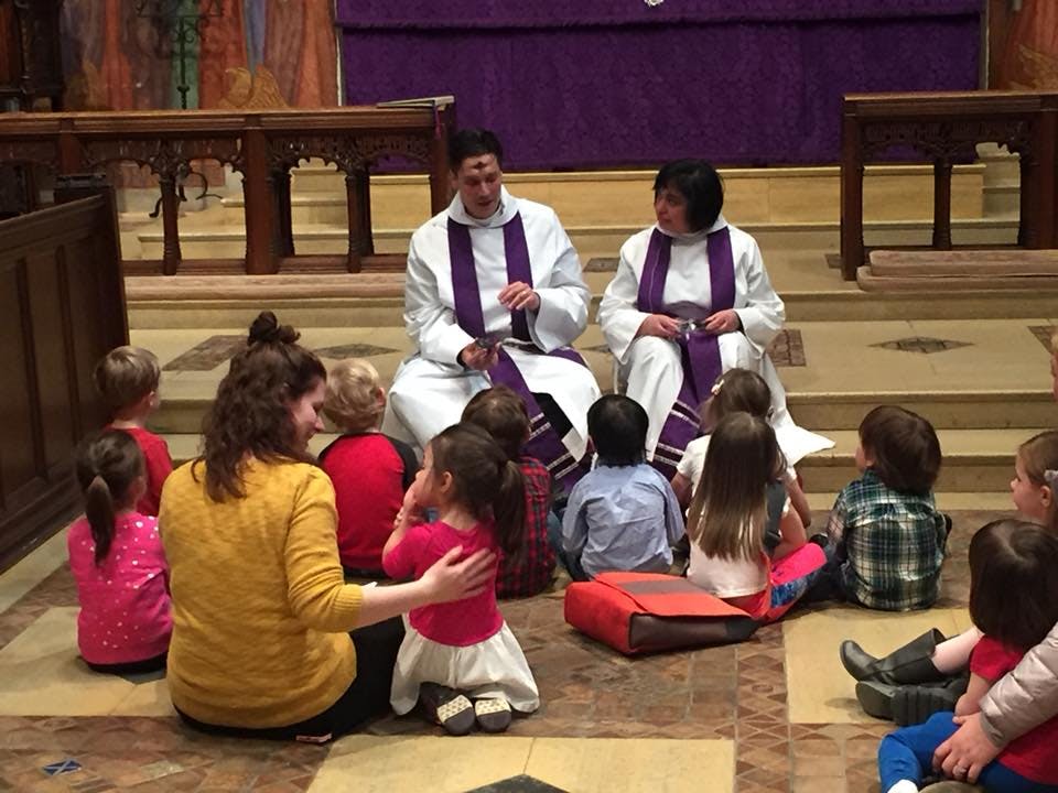 Adults and children sitting on the floor in a church