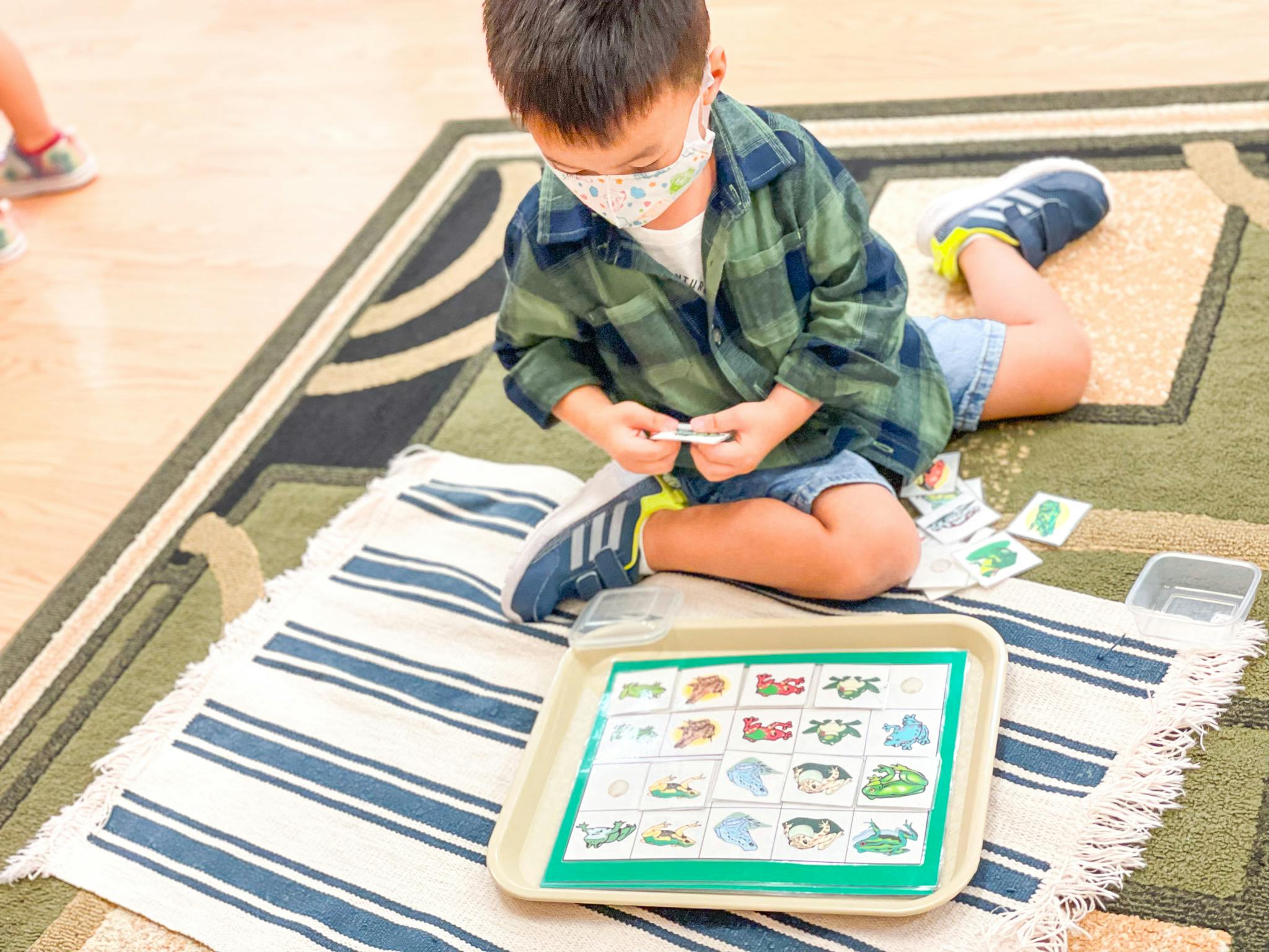 Child in a mask playing a matching game on the floor
