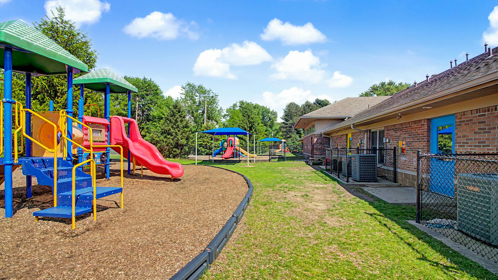 Colorful playground with slides and swings next to a brick building