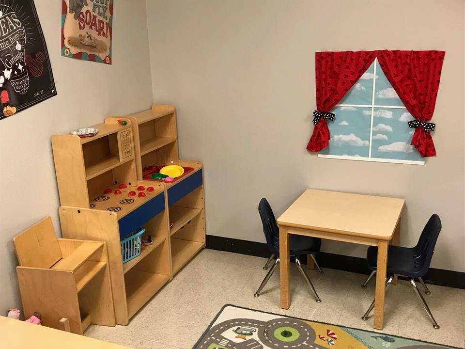 Playroom with toy kitchen, small table and chairs, and a faux window