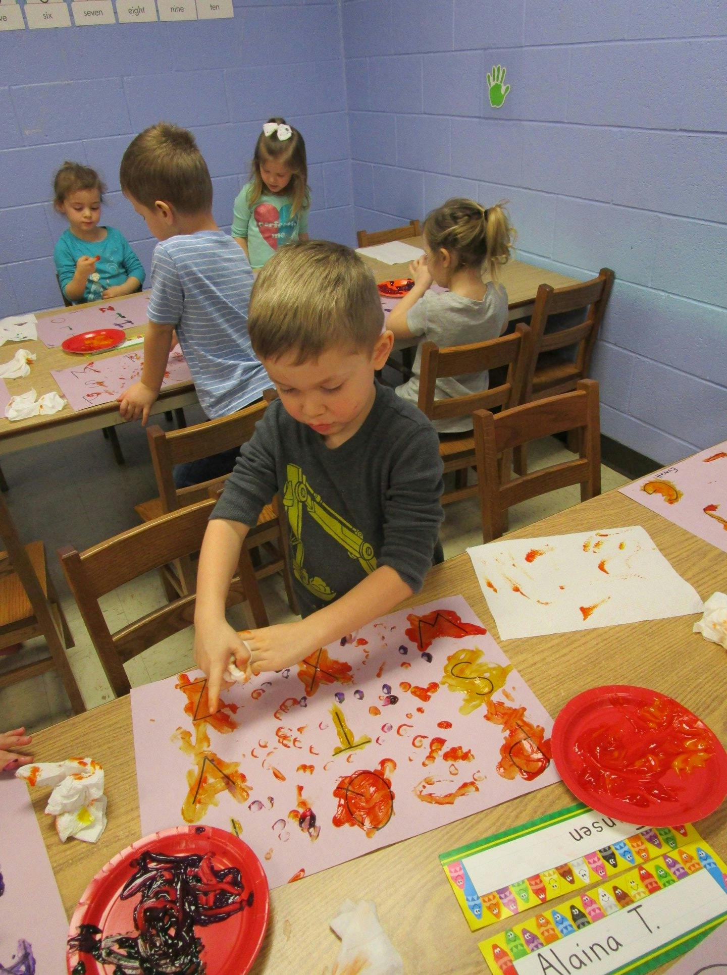 Children doing finger painting at a table