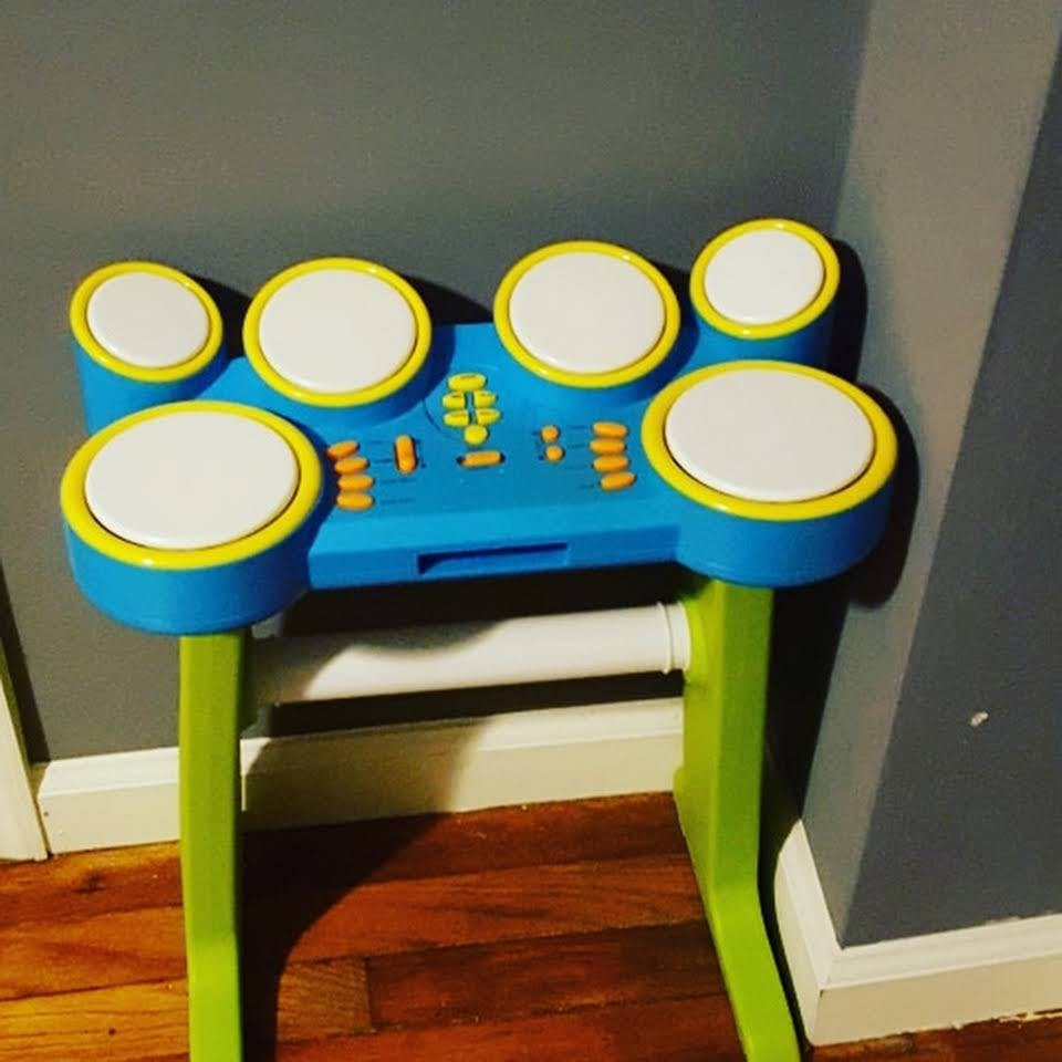 Toy drum set with blue base, white drum pads, and green legs