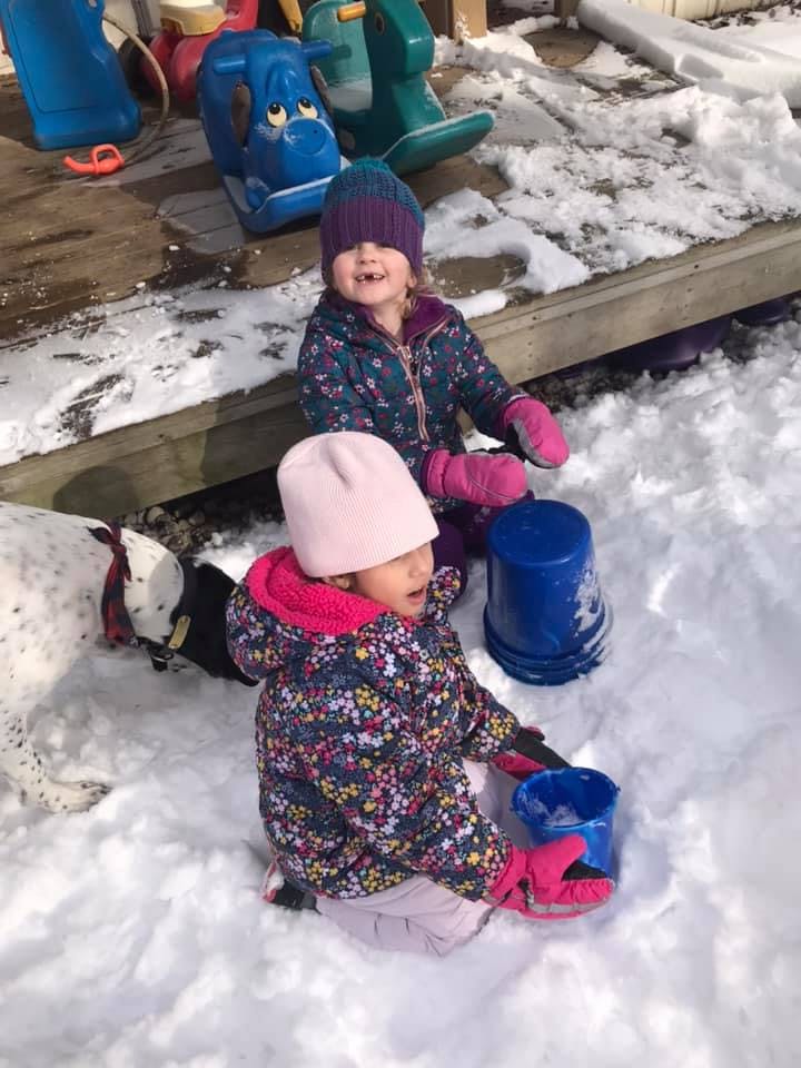 Two children playing in the snow with buckets