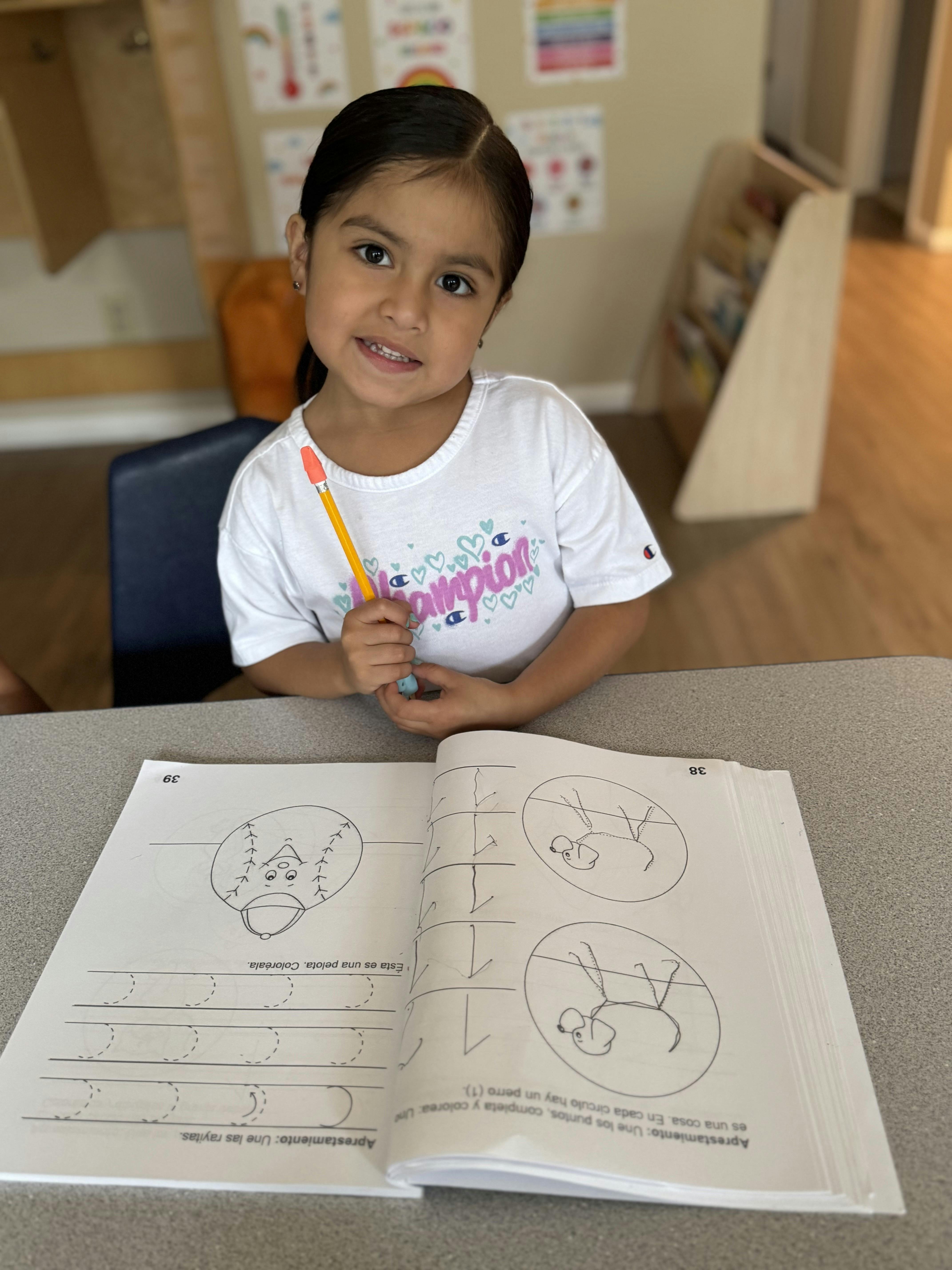 Child holding a pencil over an open workbook