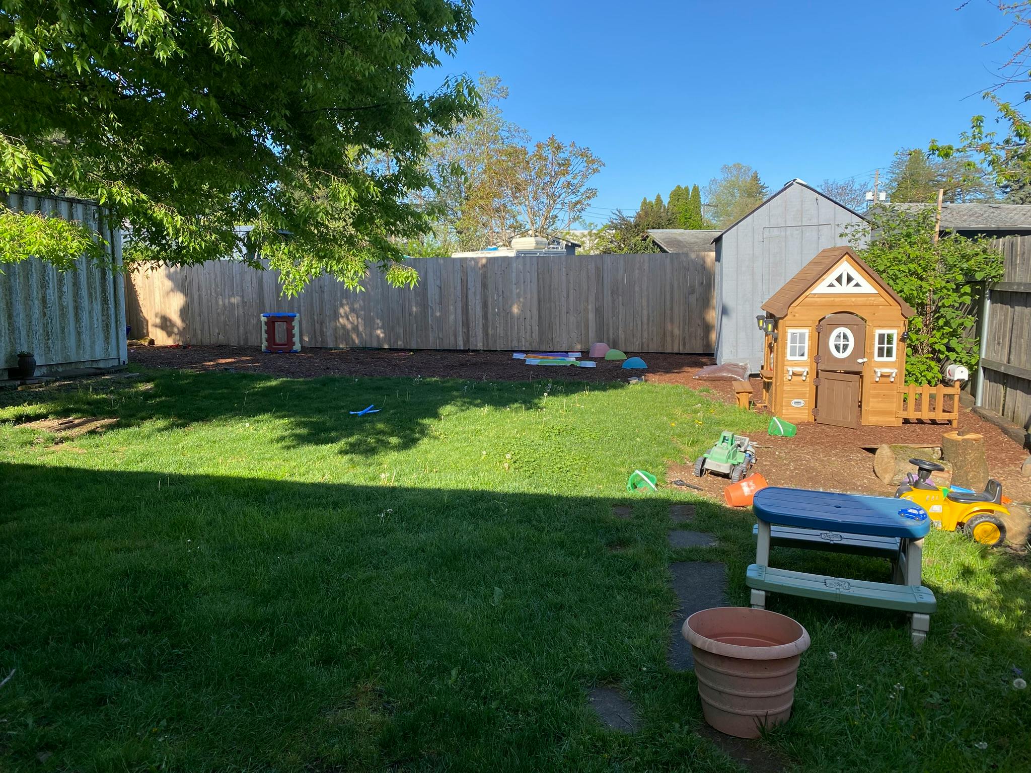Backyard with a small playhouse, toys, and a wooden fence