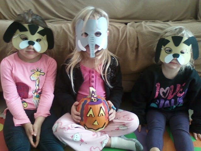 Three children wearing animal masks, one holding a pumpkin
