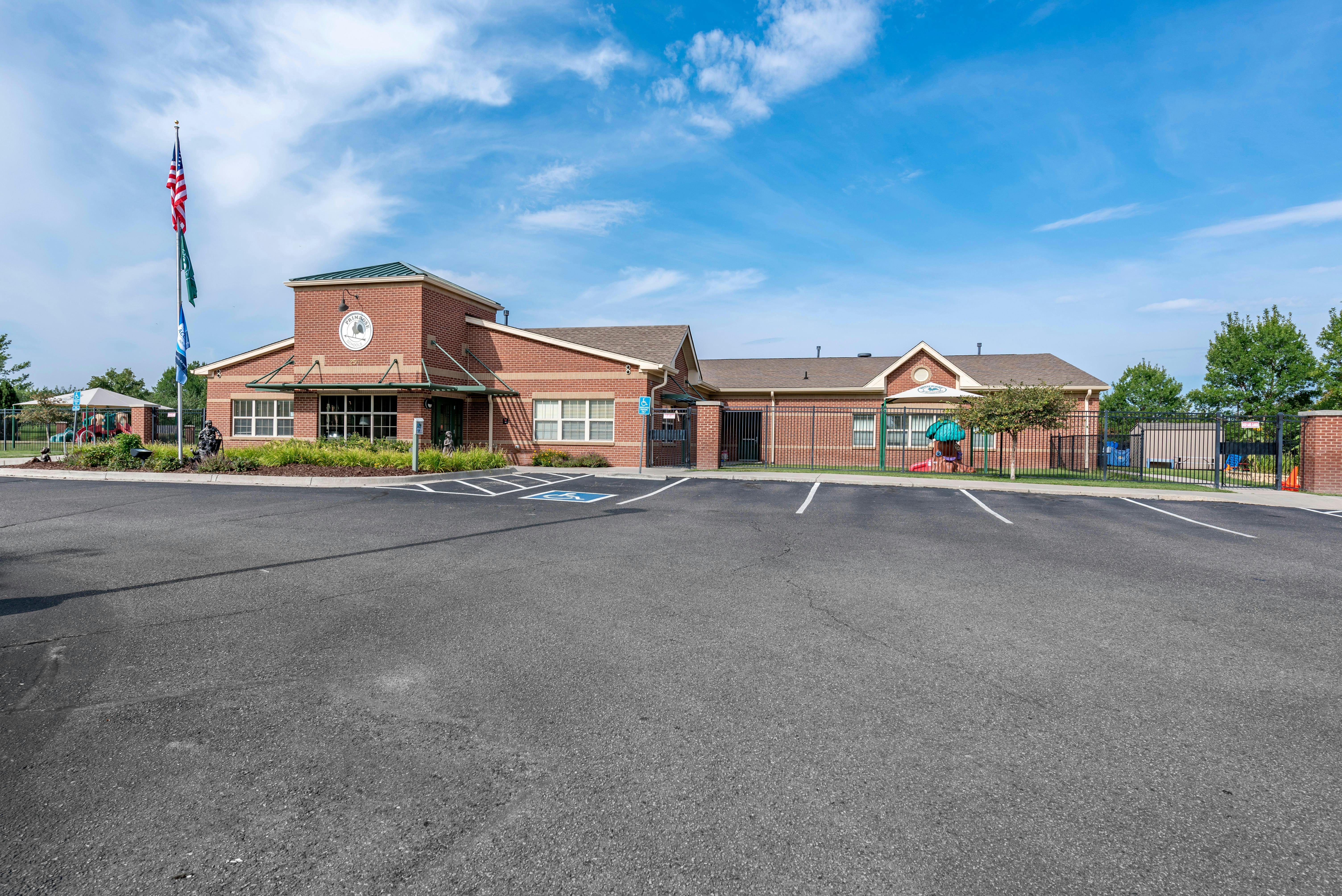 Brick building with a flagpole and a parking lot in front