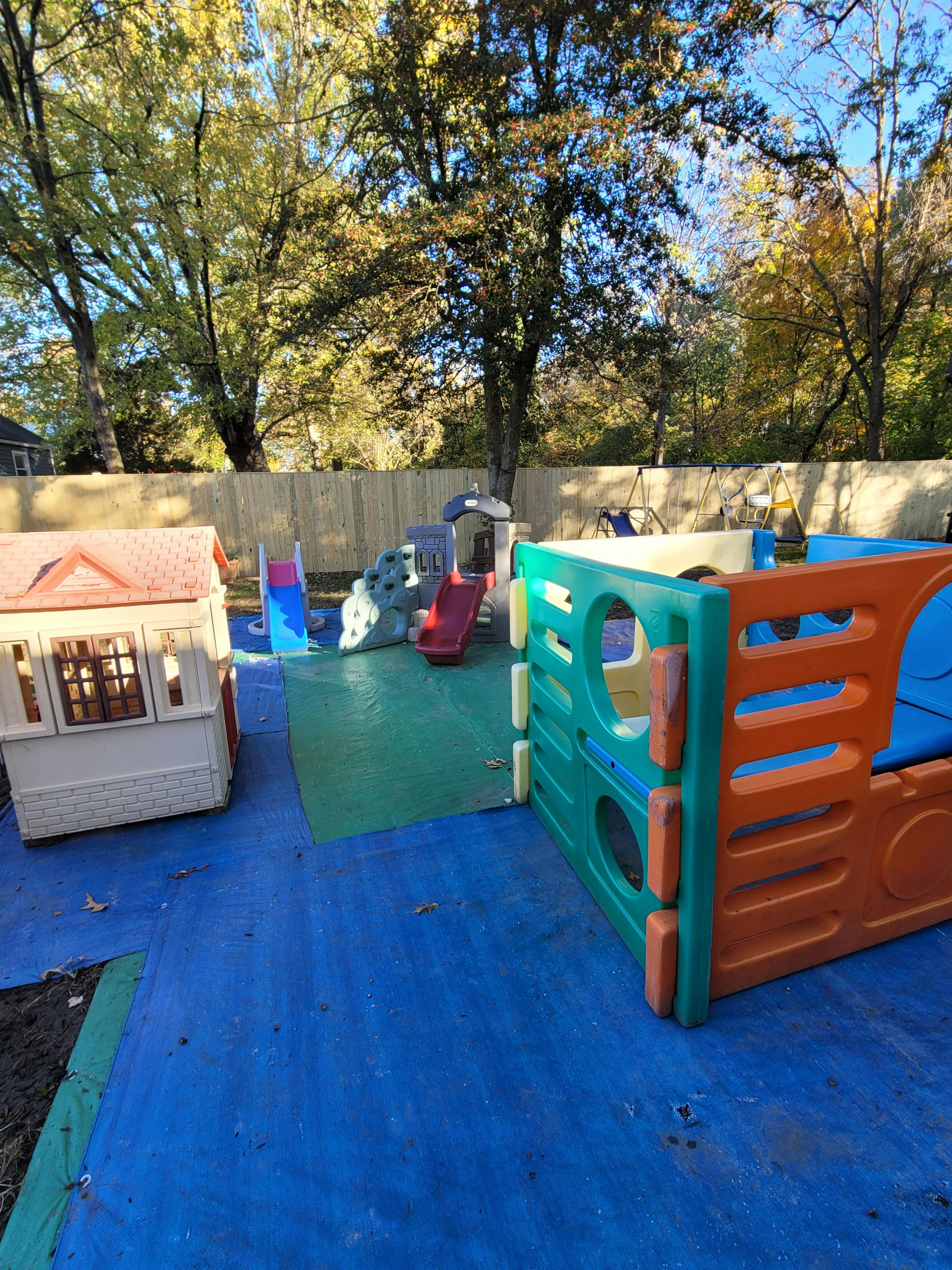 Outdoor playground with playhouses and slides on blue and green mats