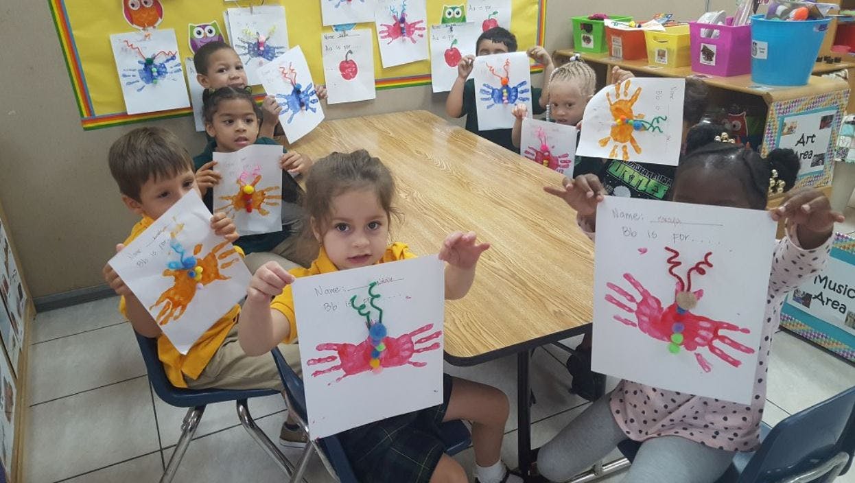 Children holding up artwork in a classroom