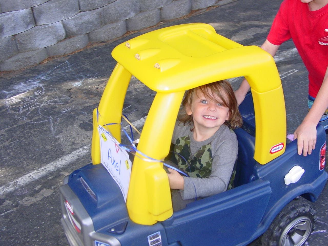 Child in a blue toy truck with a yellow roof