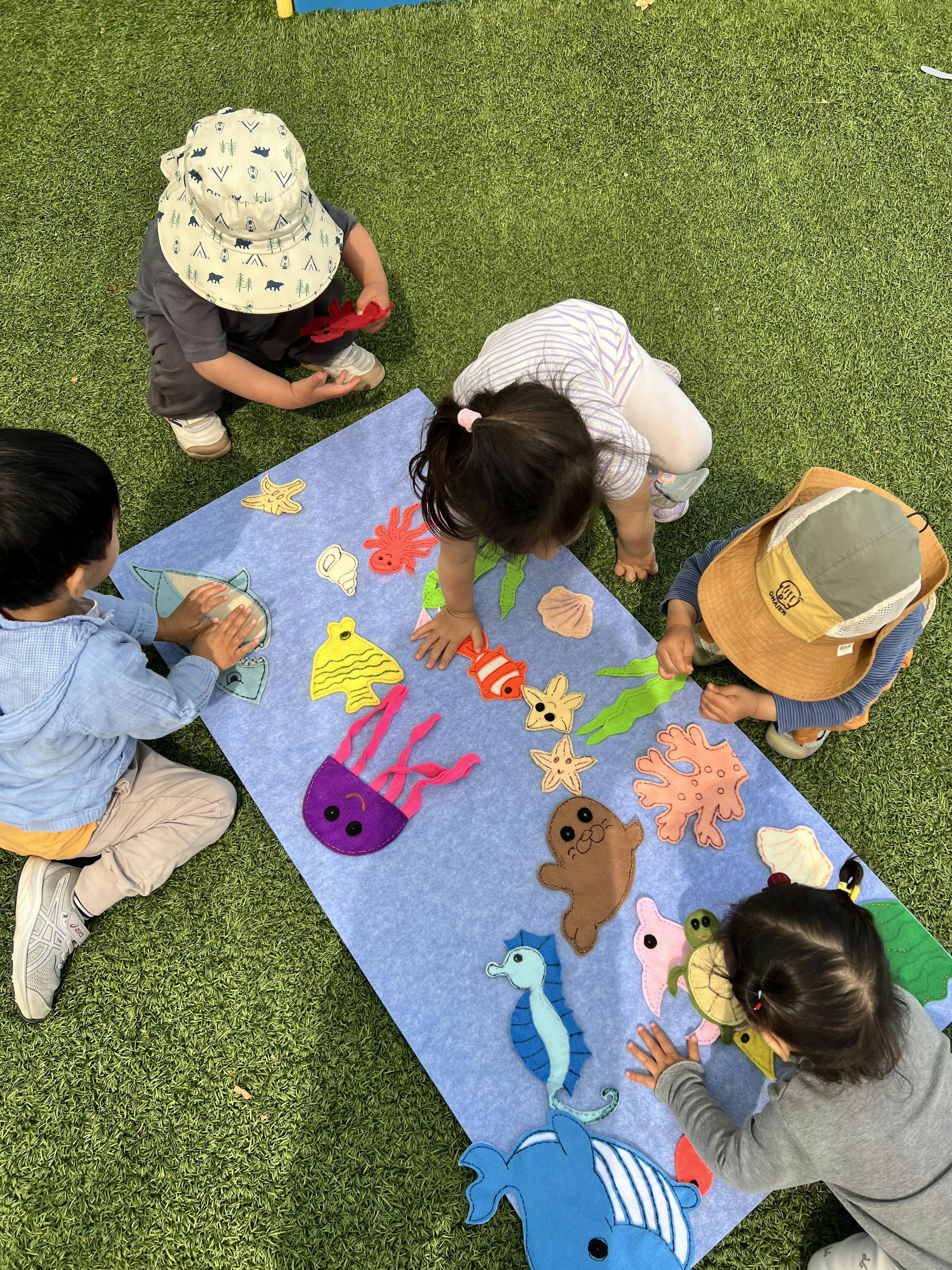 Four children playing with felt sea creatures on a blue mat