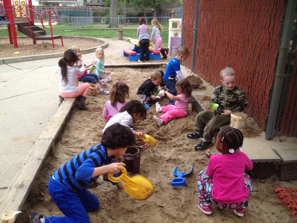 Children playing in a sandbox with toys