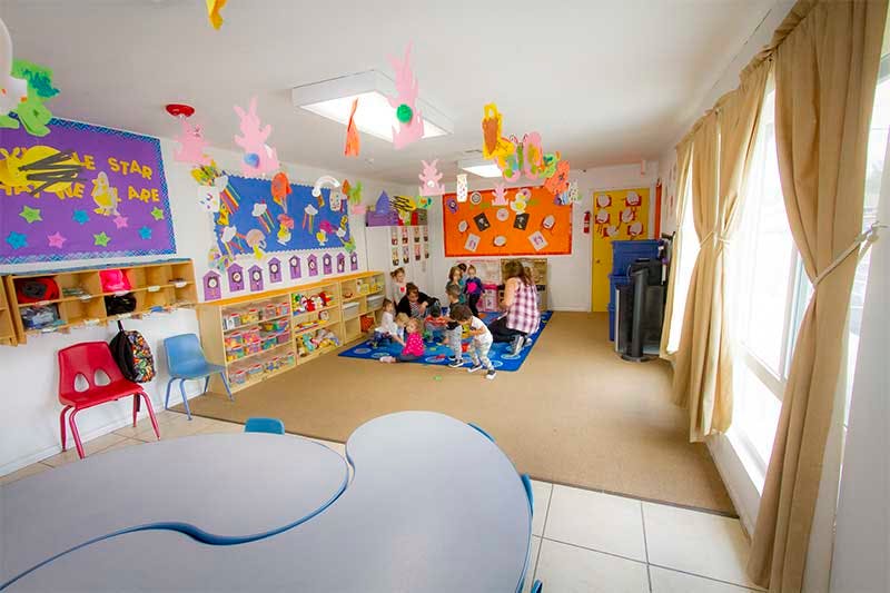 Children sitting on a blue rug in a classroom