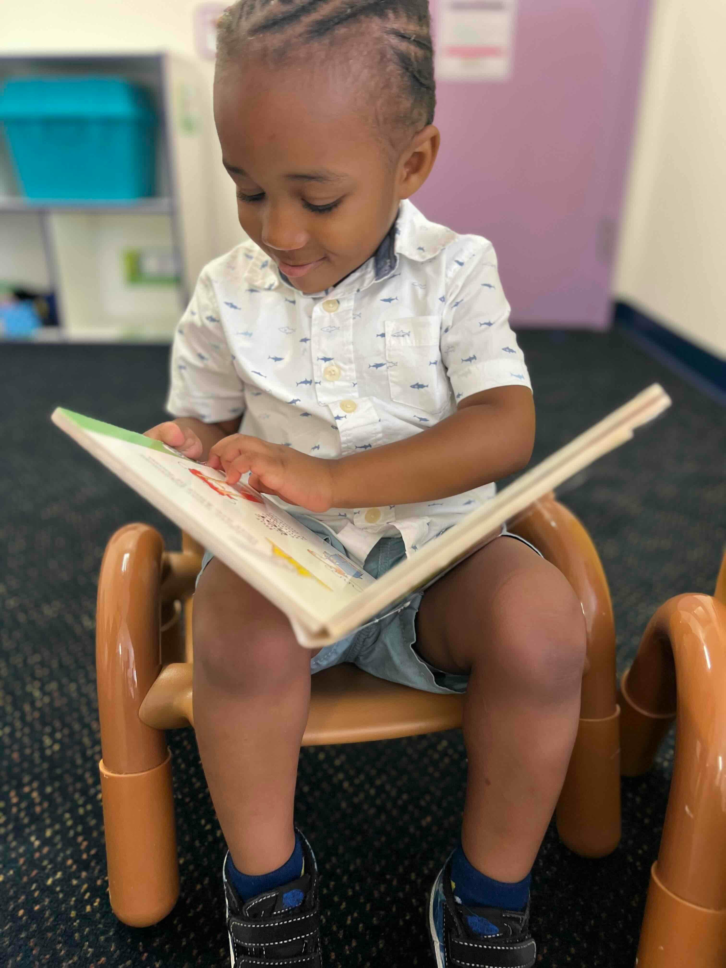 Child sitting on a small chair and reading a book