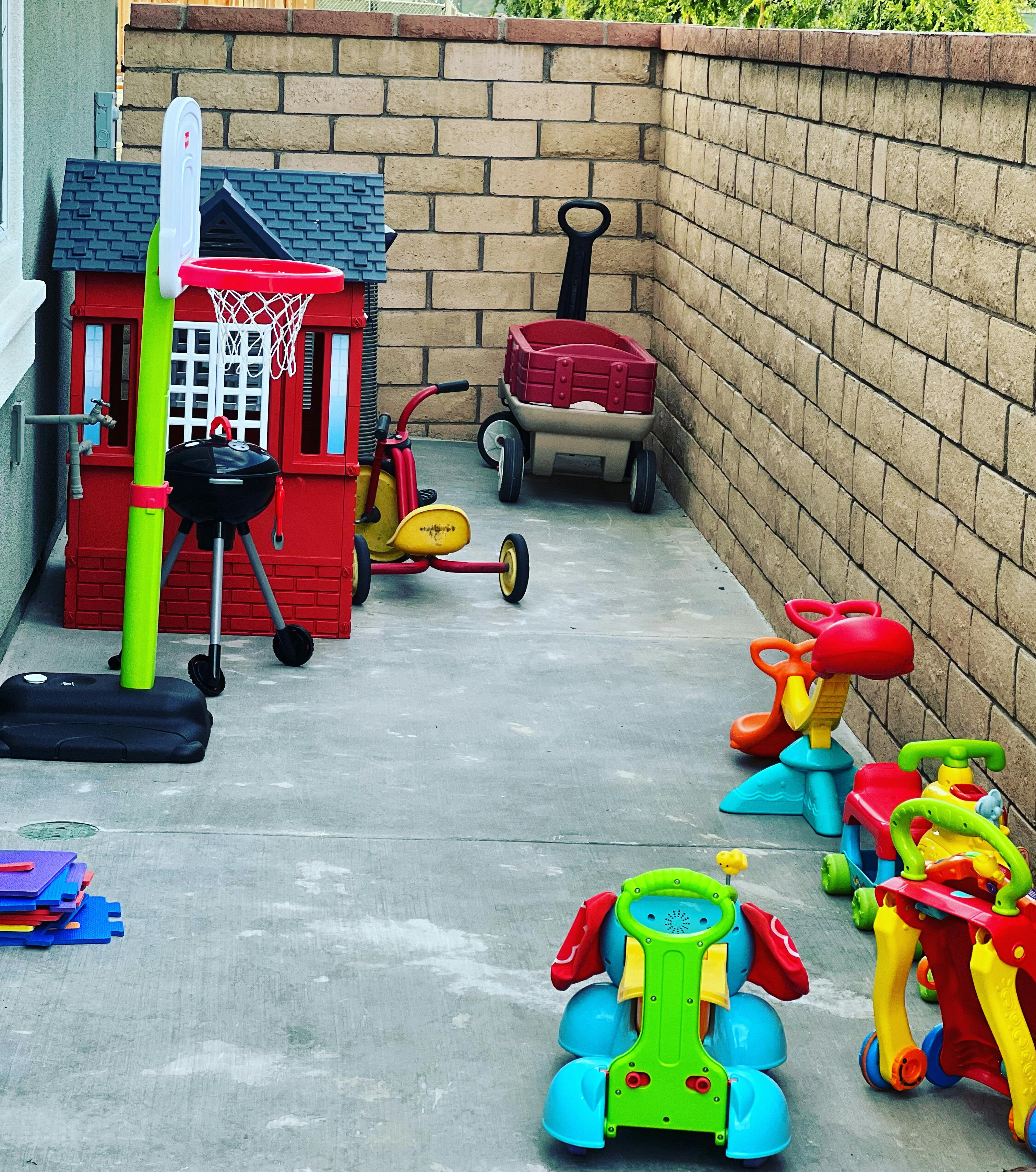 Children's play area with a playhouse, basketball hoop, and ride-on toys