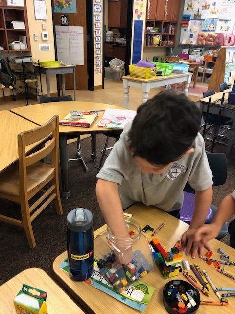 Child playing with building blocks at a table in a classroom