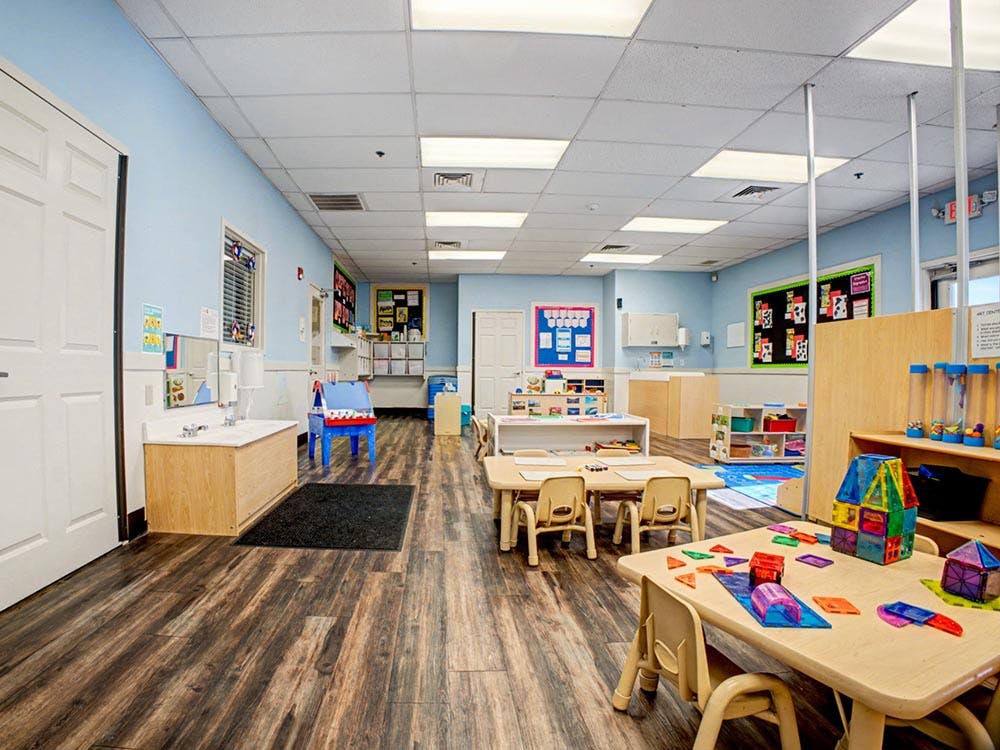 Classroom with small tables and chairs, shelves, and art supplies