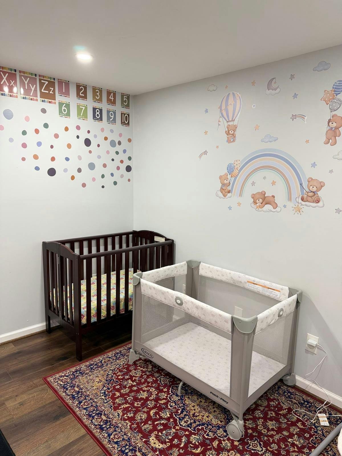 Crib and playard in a nursery with colorful wall decals