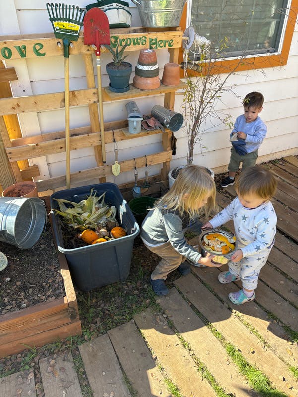 Two children holding a bowl of gourds, another child standing nearby