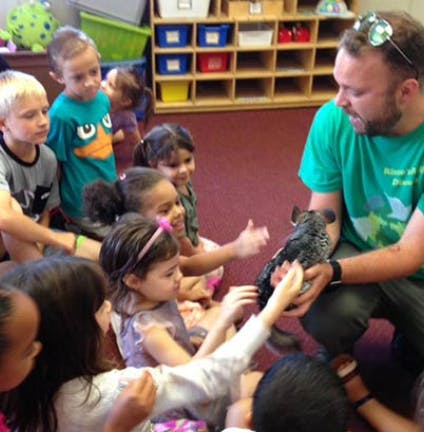 Adult holding an animal for children to see in a classroom